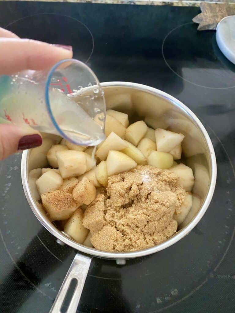 Adding lemon juice to a small saucepan filled with pears, brown sugar, salt and nutmeg for Caramel Pear Butter.