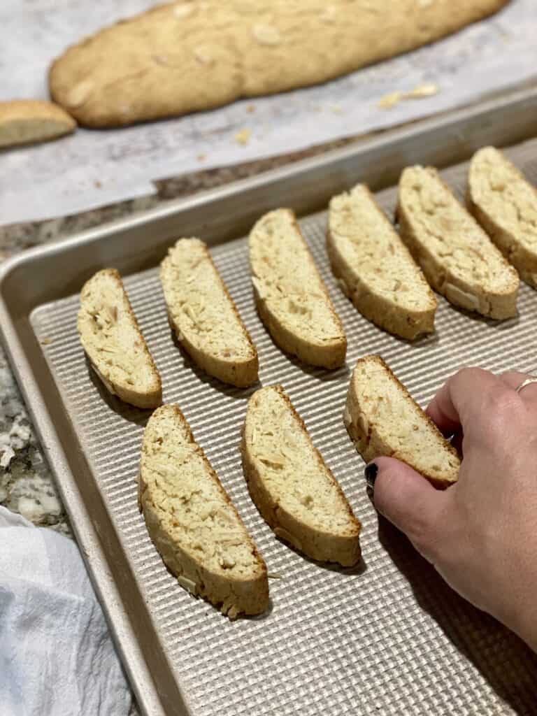 Flipping baked Amaretto Biscotti on the baking pan for the second bake .