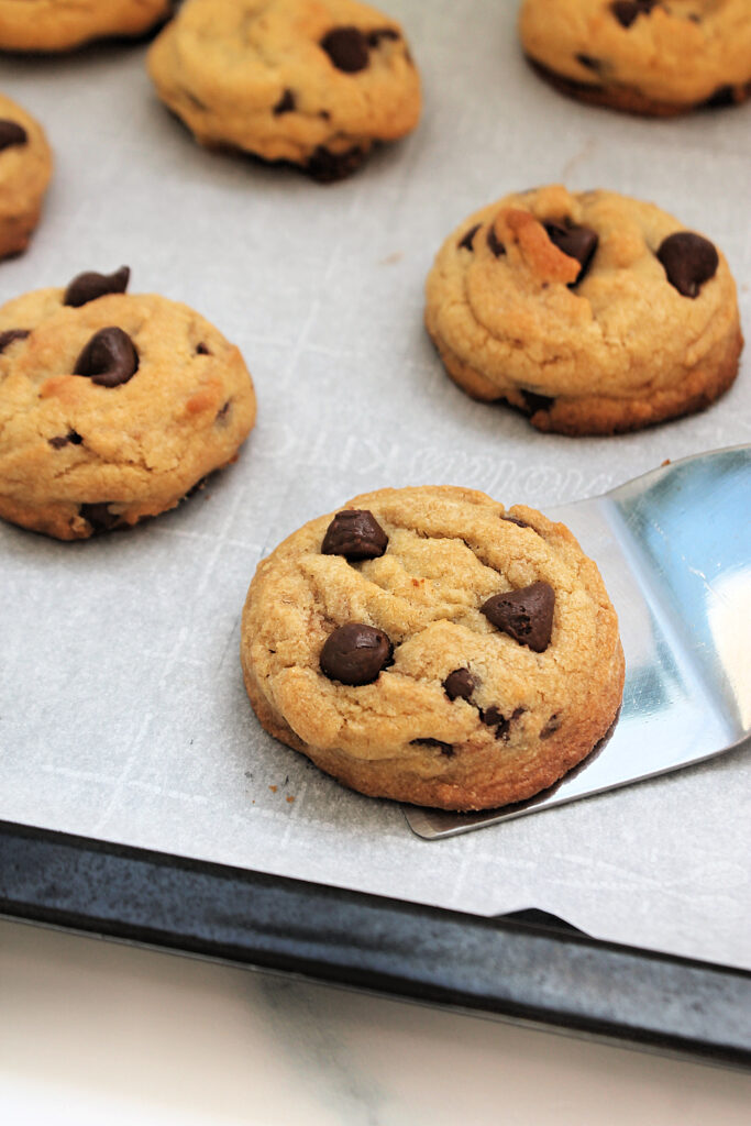 Chocolate chip cookies that were baked in the air fryer on a pan lined with parchment paper.