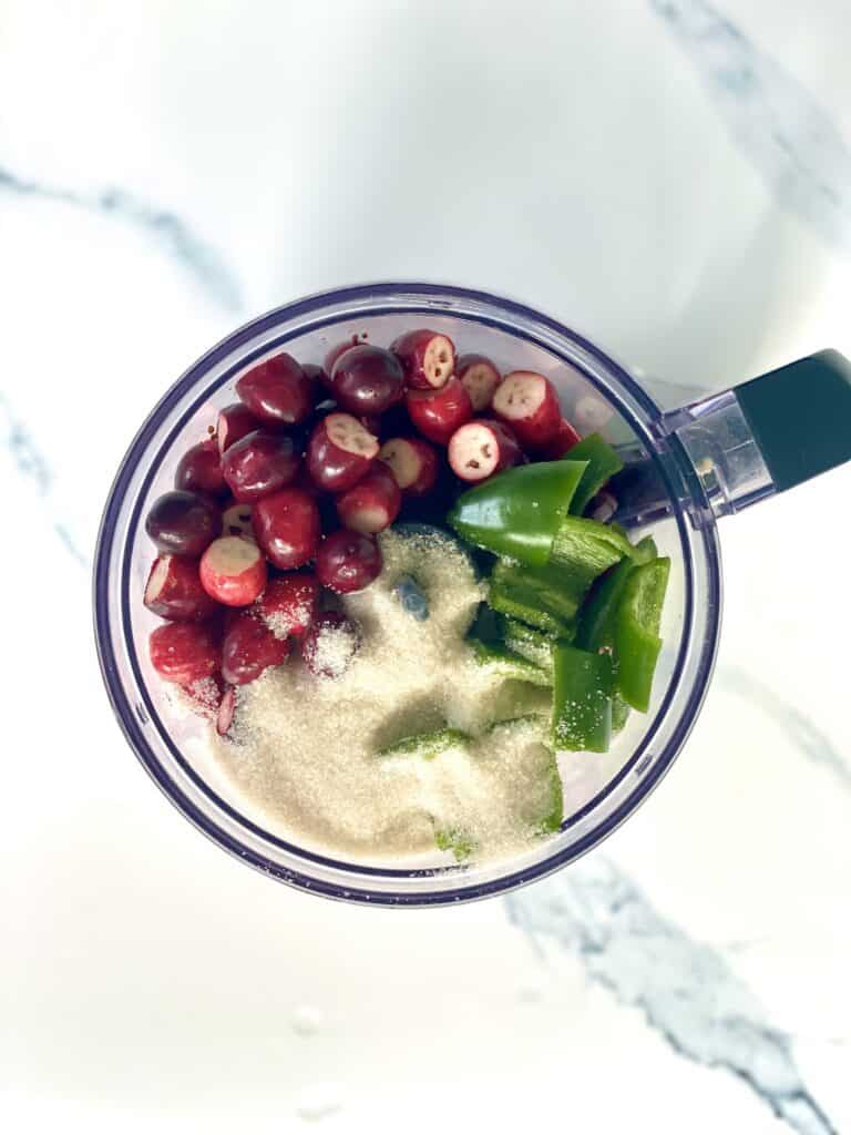 Ingredients for Cranberry Jalapeno Dip in the bowl of a food processor before processing.