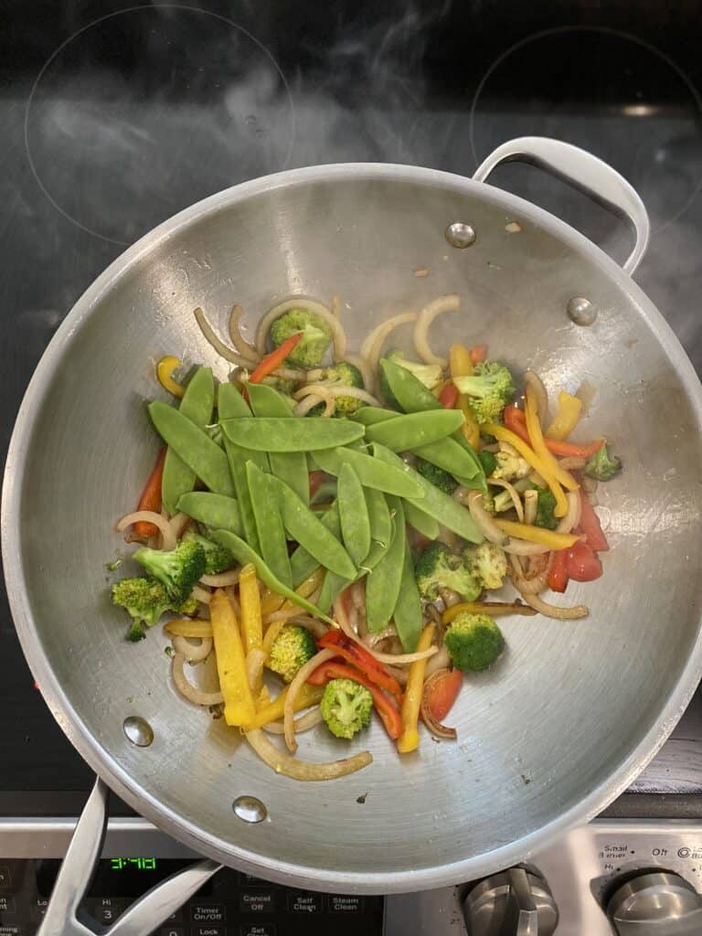 Snow peas added to vegetable mixture in wok.