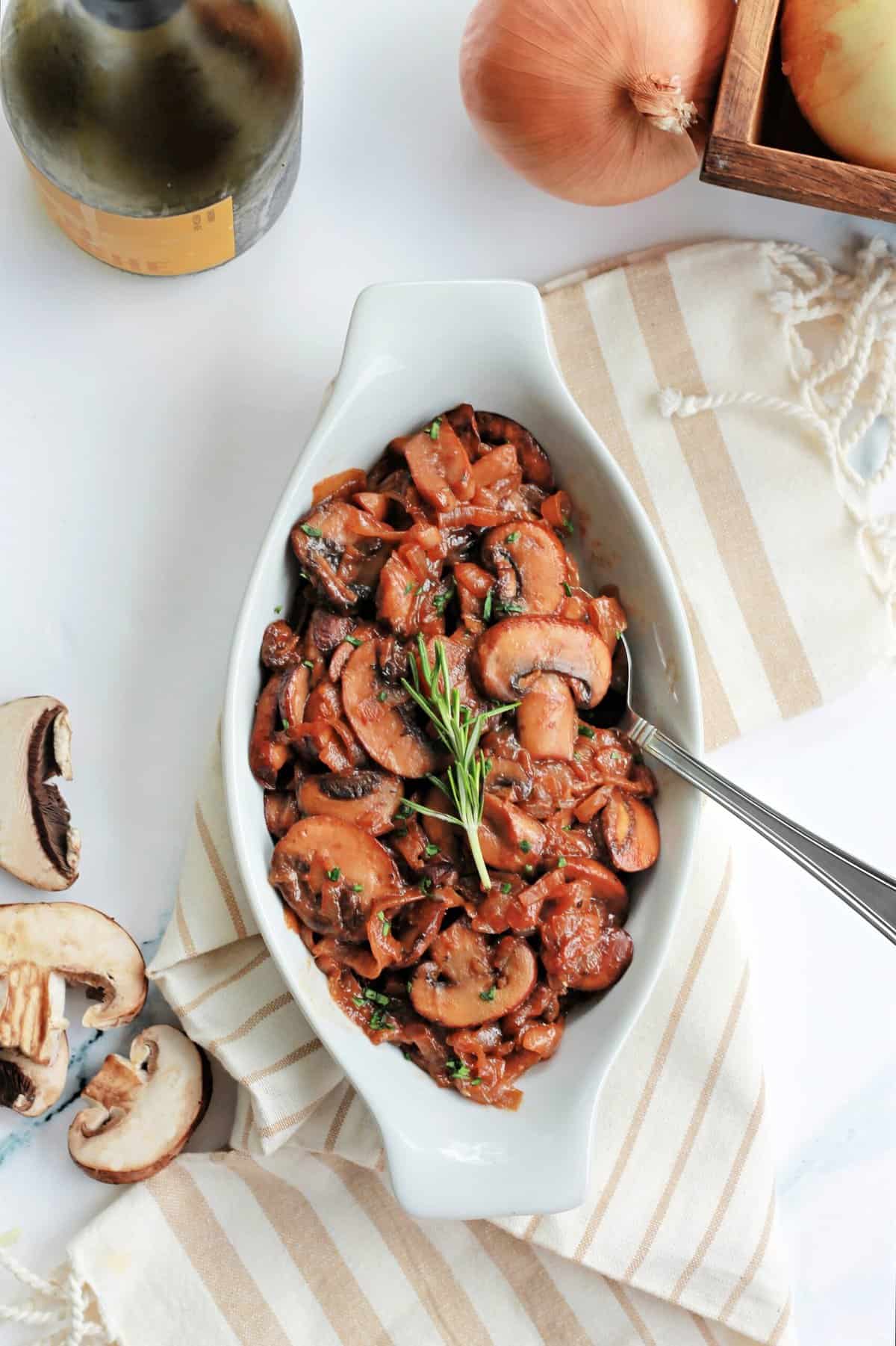 Caramelized Onions and Mushrooms in a white dish on a striped tea towel.