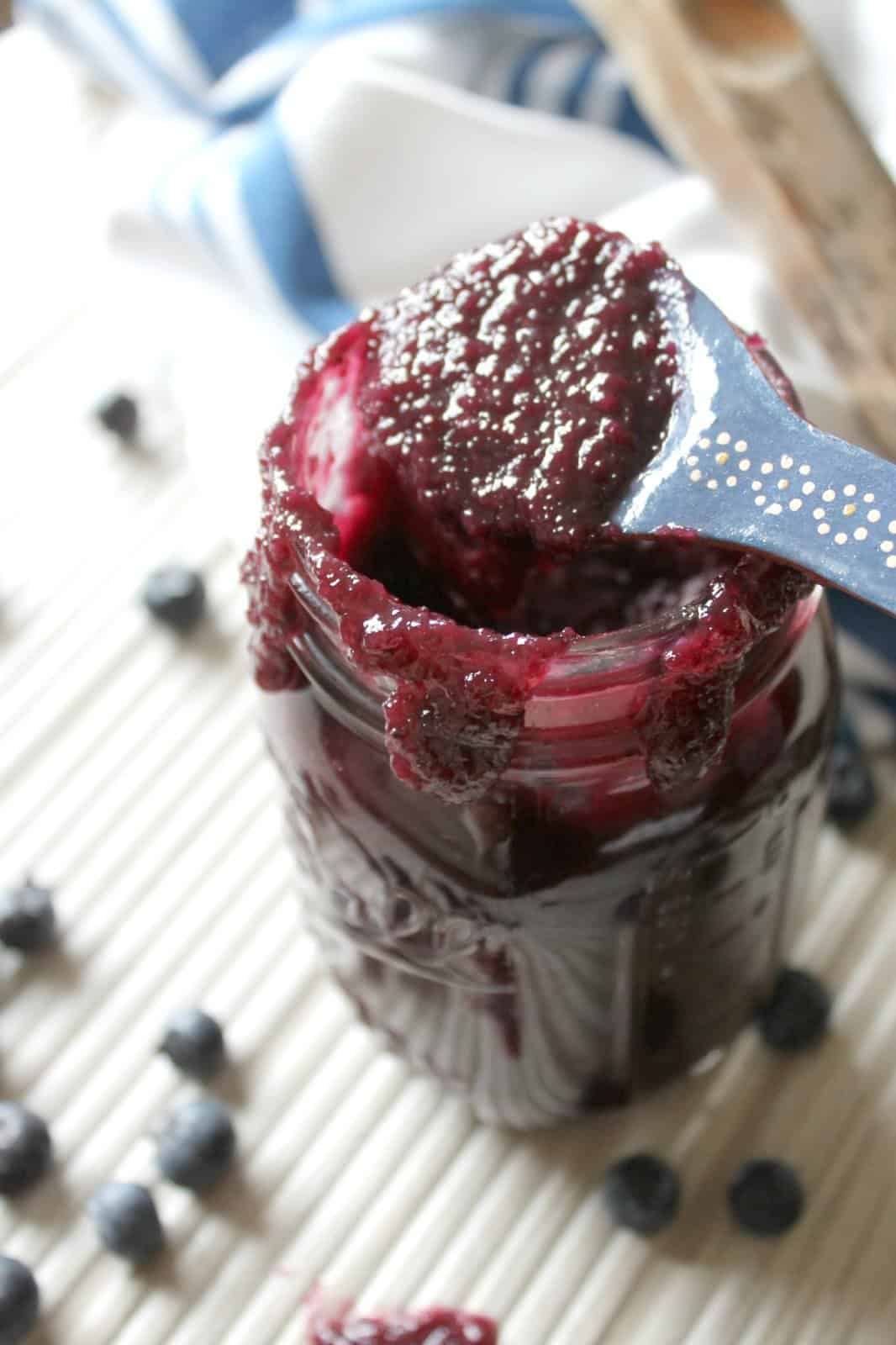 A blue ceramic spoon scooping out blueberry bbq sauce to show texture.