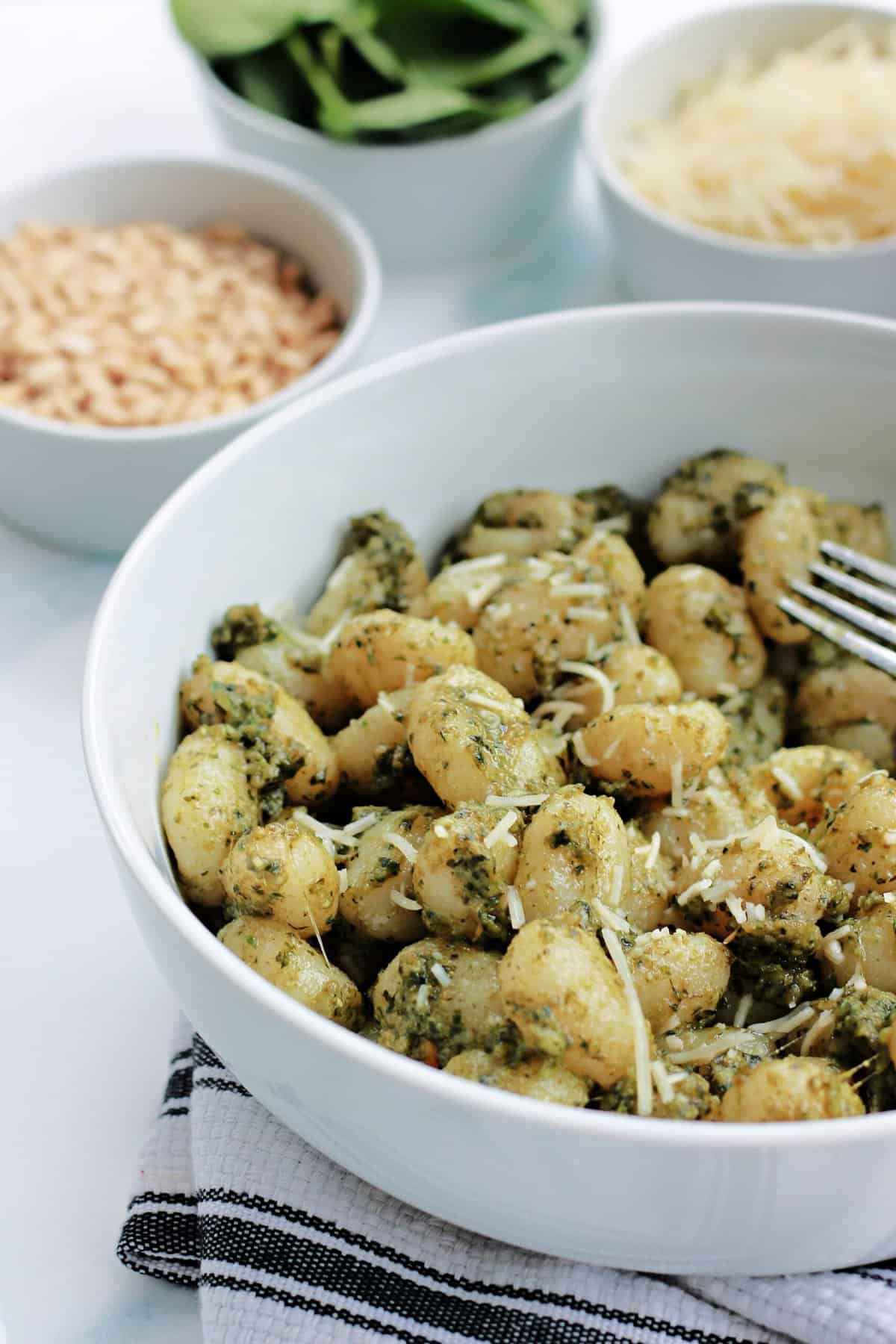 A close up shot to show texture of pesto gnocchi in a white bowl.