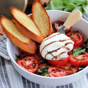 Burrata Caprese and toasted bread in a white bowl .