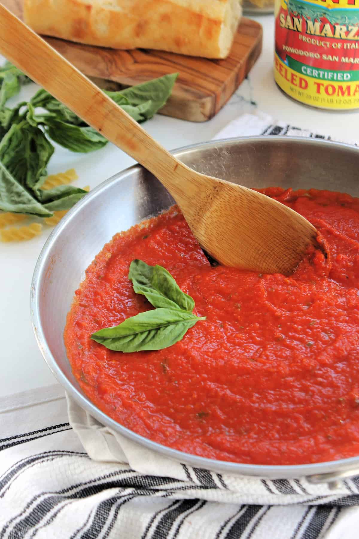 A wooden spoon stirring San Marzano Tomato Sauce in a pan.