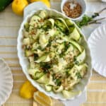 Zucchini Ribbon Salad in a white serving dish surrounded by lemons and other ingredients.
