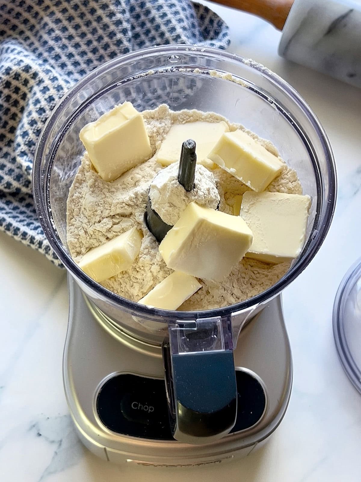 Cubes of cold butter in a food processor filled with flour.
