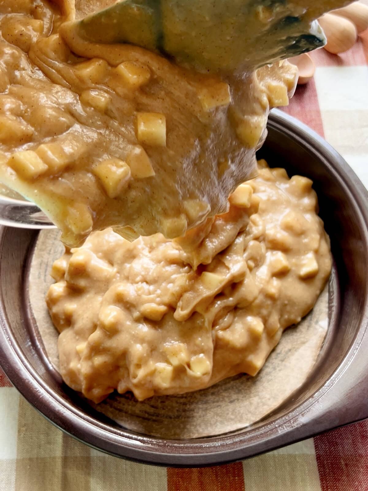 Pouring the apple spice cake batter into a parchment lined baking pan.