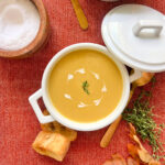 Overhead shot of butternut squash soup in a small white pot.