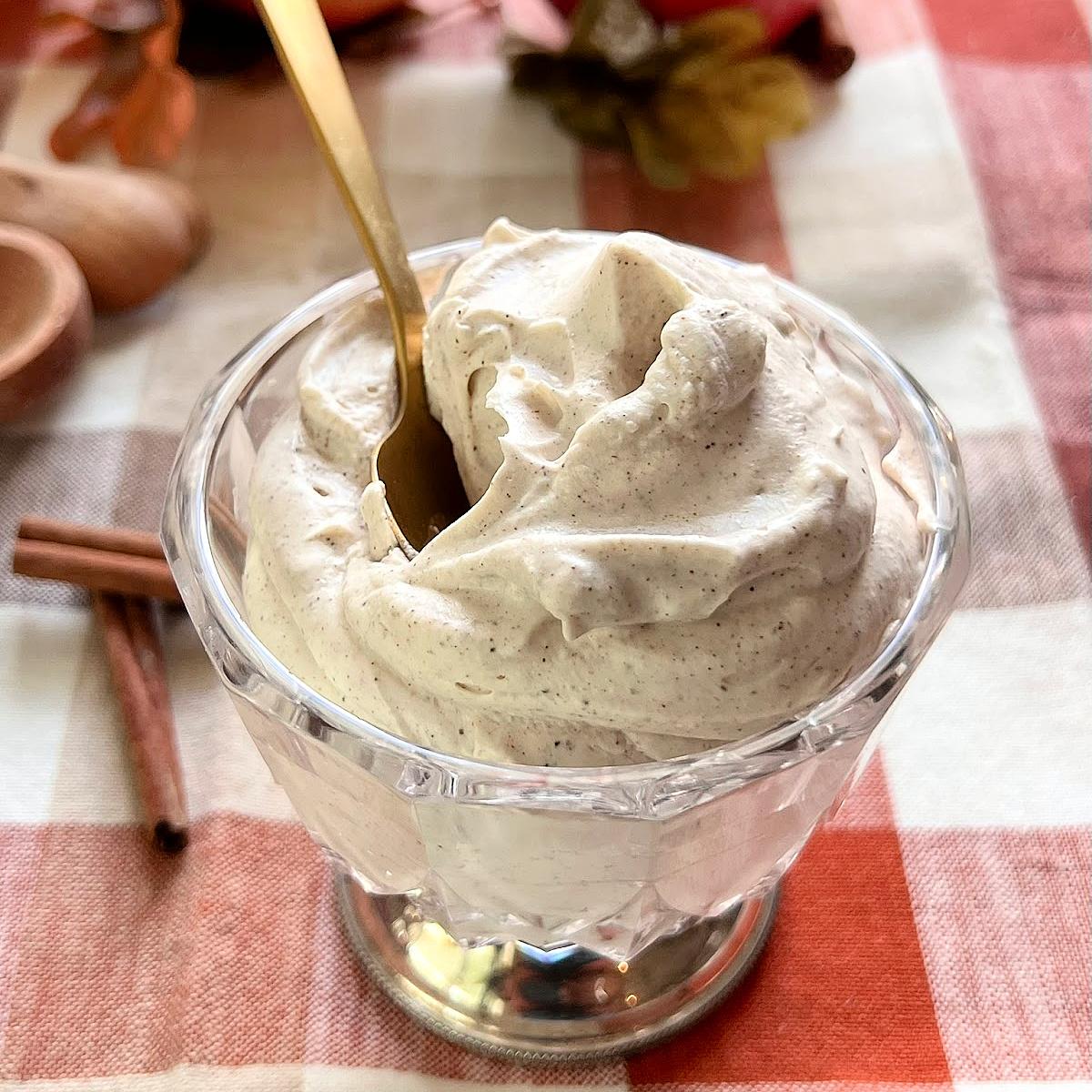 A crystal container filled with Cinnamon Whipped Cream on a fall holiday table.