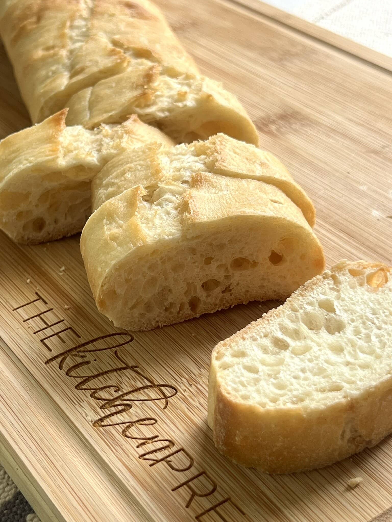 Sliced baguette on a cutting board to show thickness needed for garlic crostini.