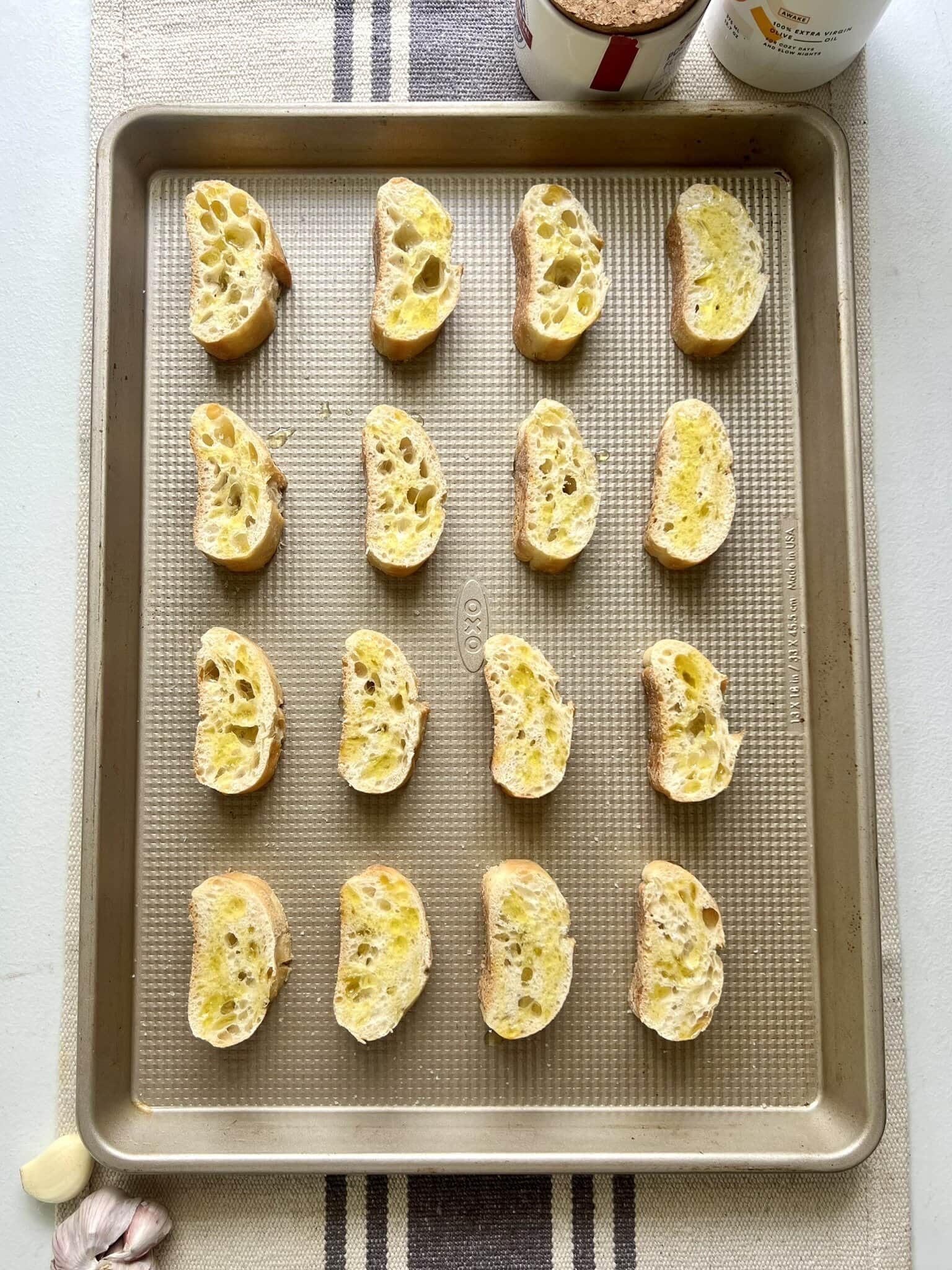Baguette slices on a baking pan ready to be baked into crostini.