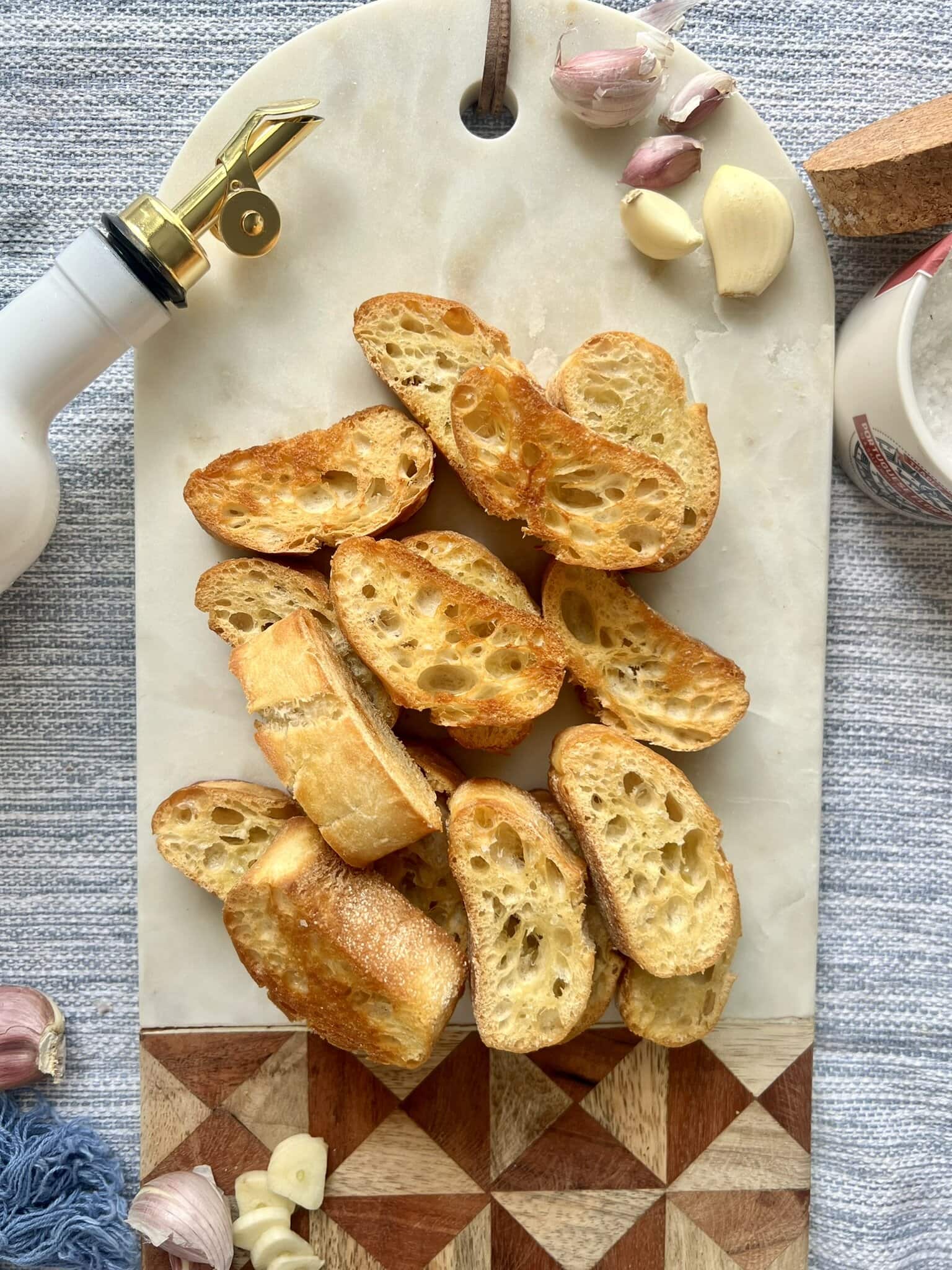 Overhead shot of garlic crostini on a decorative marble and wood board.