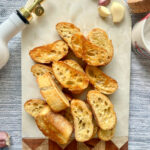 Overhead shot of garlic crostini on a decorative marble and wood board.