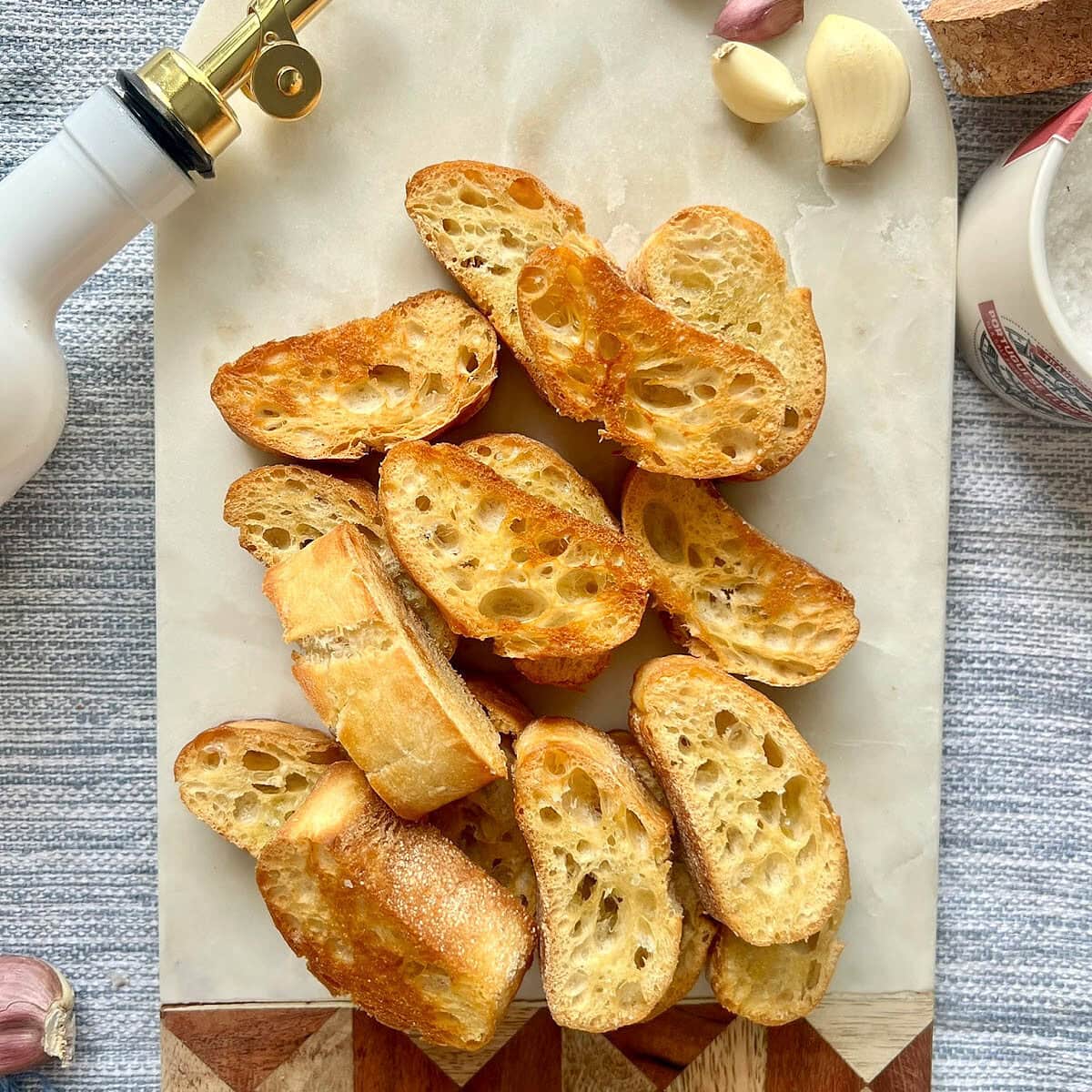 Overhead shot of garlic crostini on a decorative marble and wood board.