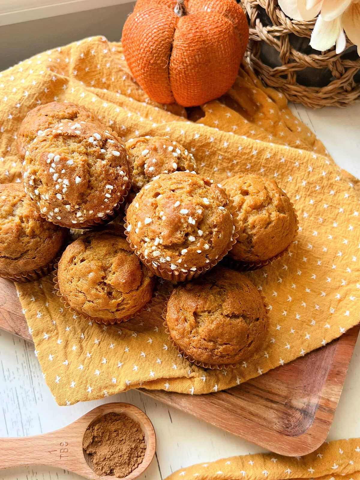 A pile of Pumpkin Banana Bread Muffins on a yellow napkin.