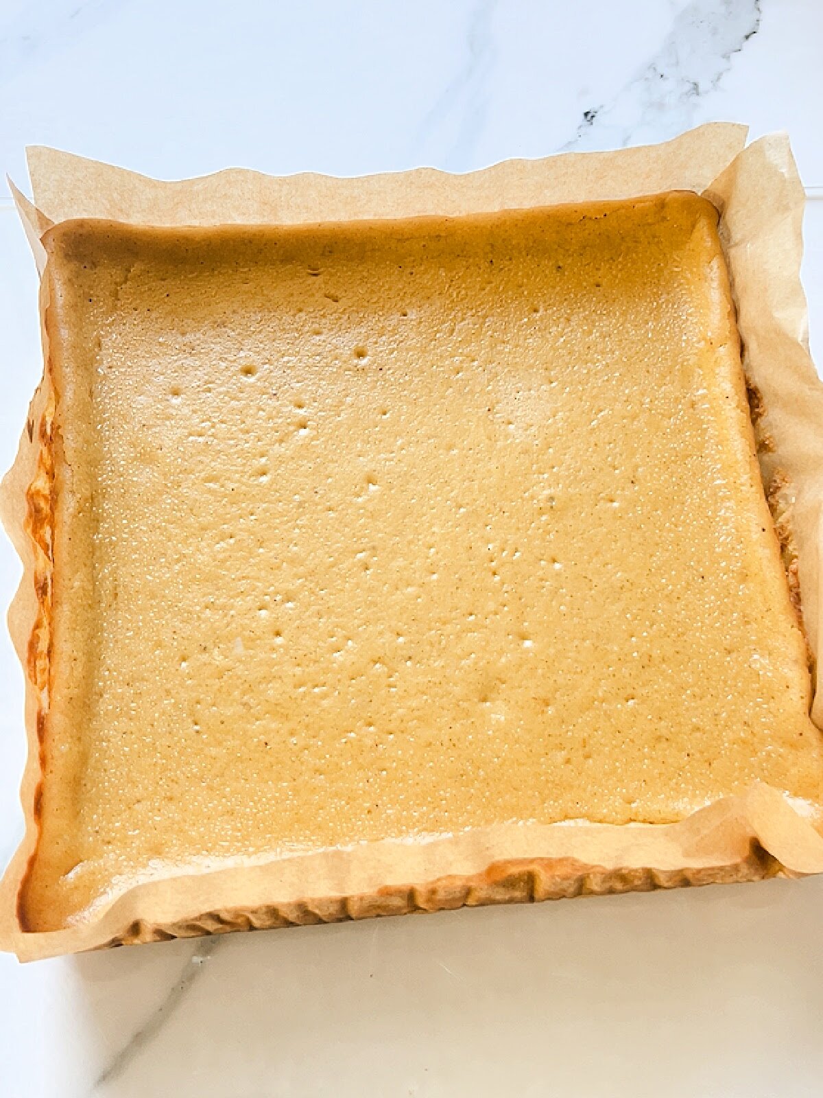 Baked pumpkin cheesecake bars before cutting to show texture once baked at cooled.