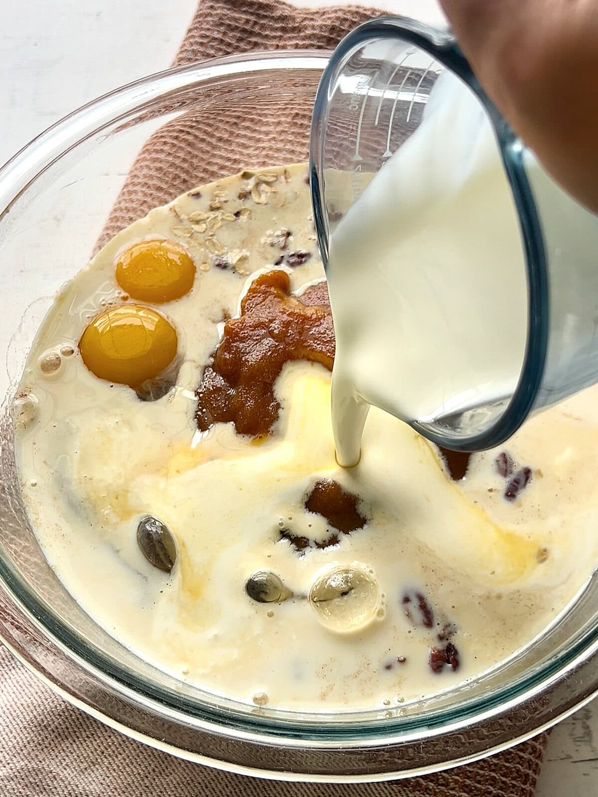 Adding milk and cream to the mixture for Pumpkin Baked Oatmeal.