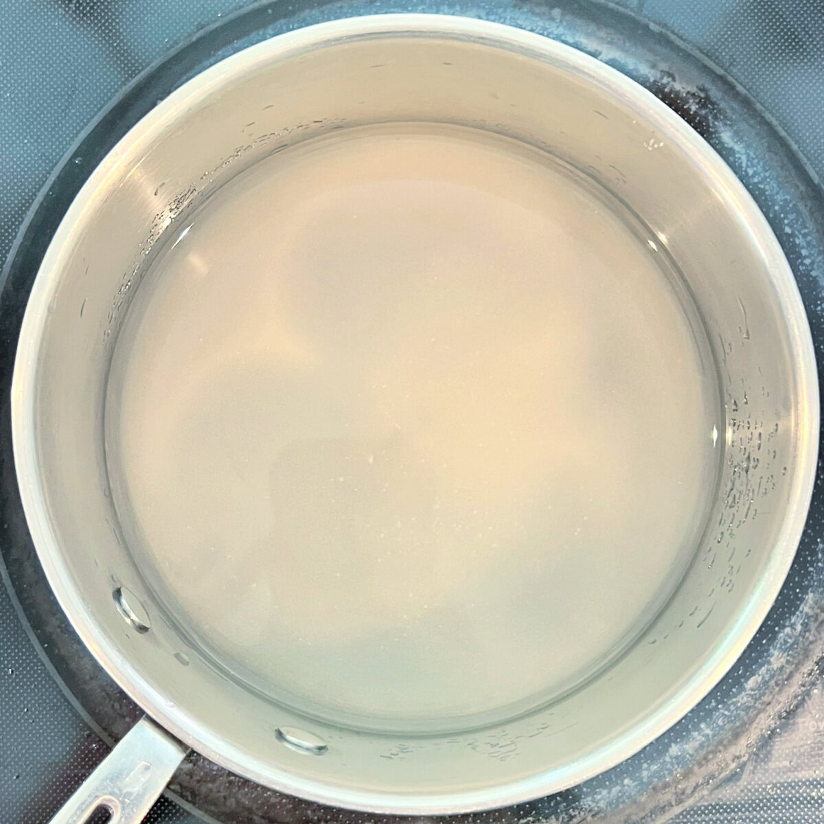 Simple syrup being made in a saucepan for raspberry sorbet.