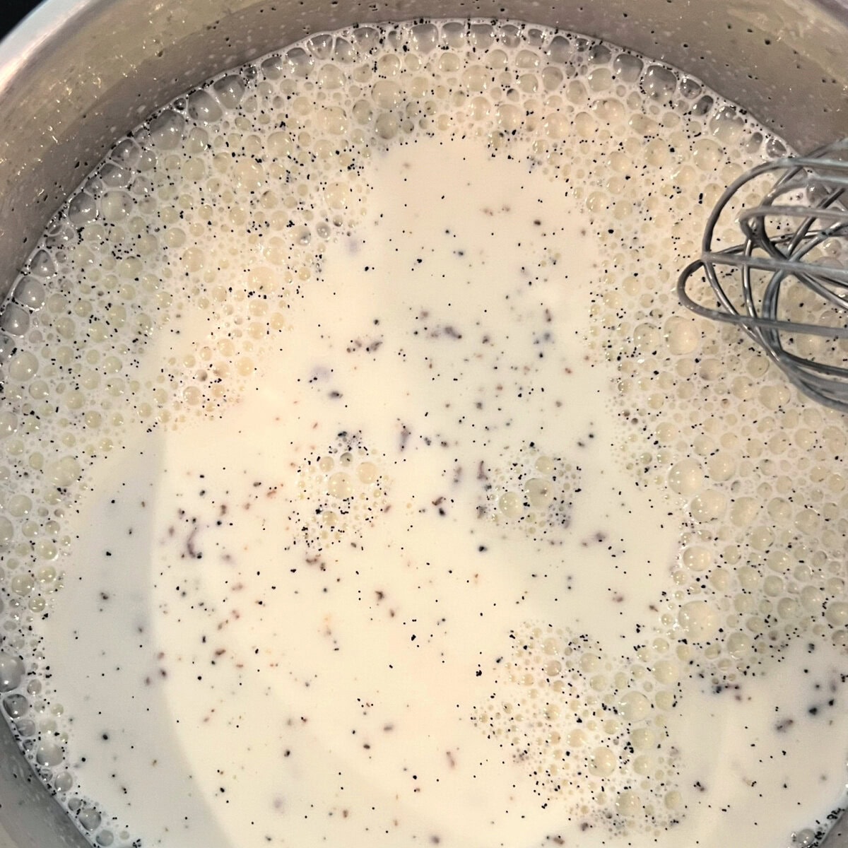 Milk, cream, sugar and vanilla beans combined in a saucepan for vanilla bean panna cotta.