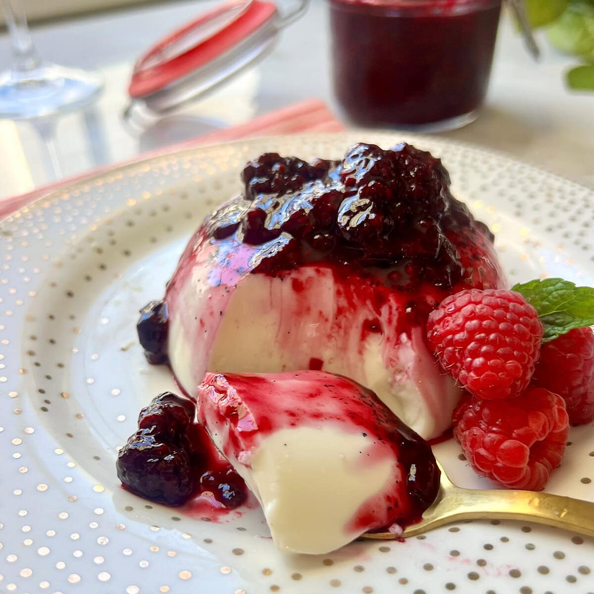 Vanilla Bean Panna Cotta topped with mixed berry compote on a plate.