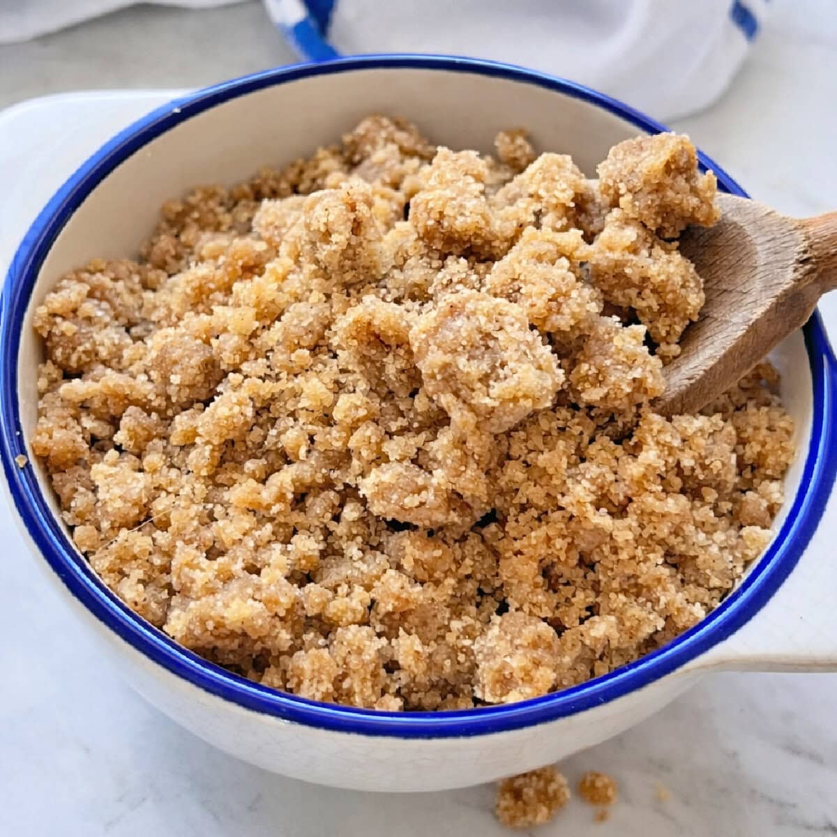 Cinnamon Streusel in a bowl with a wooden spoon.