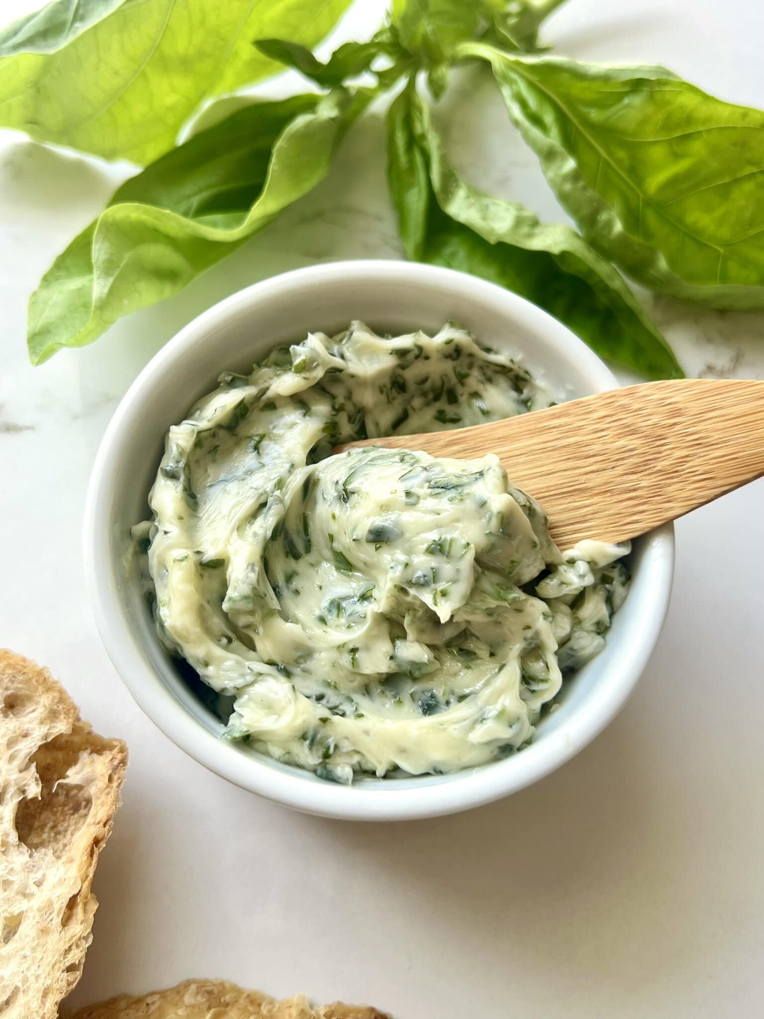 Basil Butter being scooped out of a small ramekin with a spreading knife.